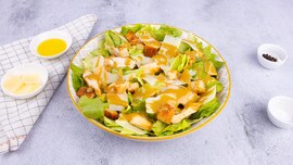 piatto con insalata, pollo, crostini di pane, parmigiano e salsa